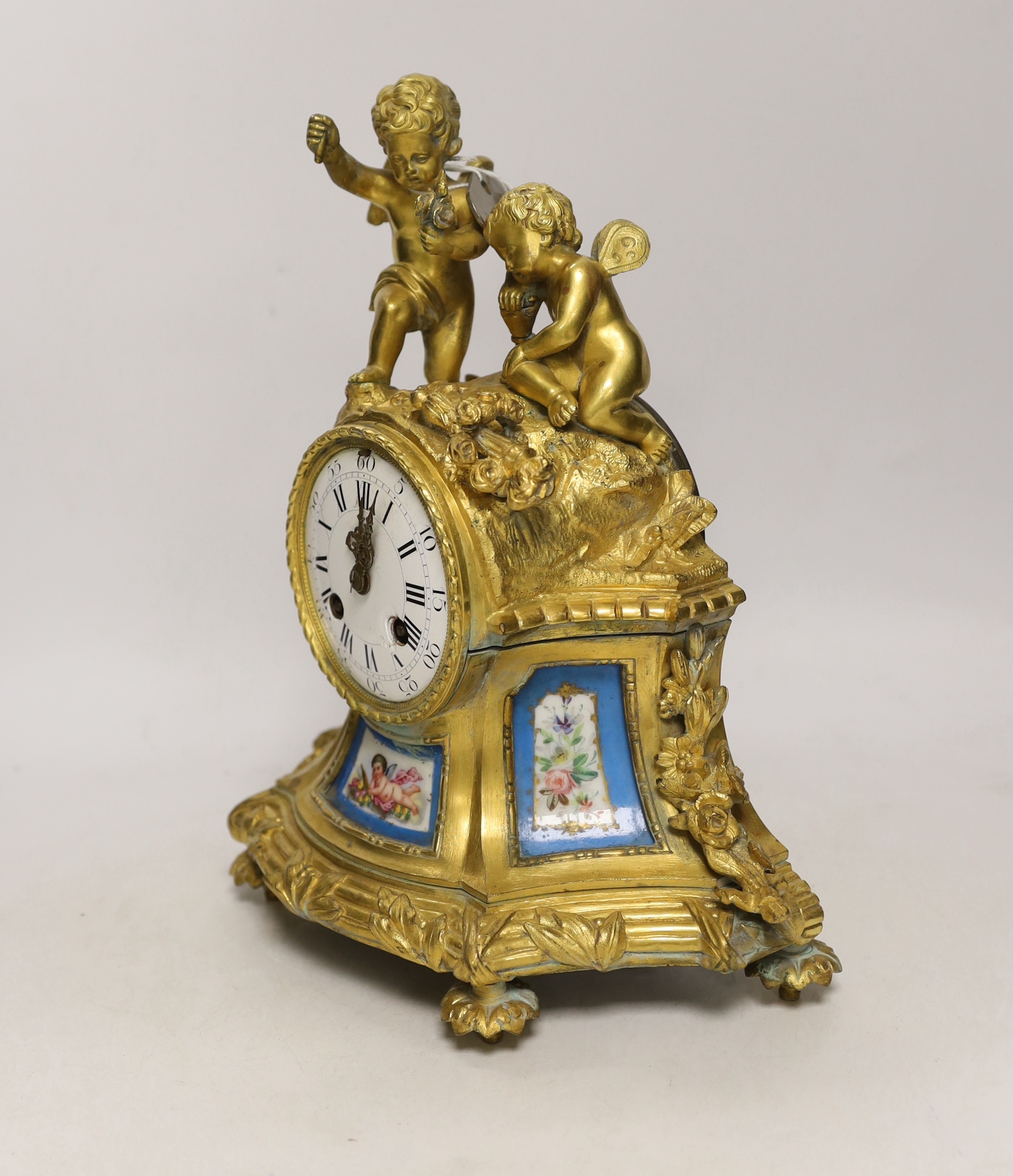 A French gilt metal enamel mantel clock surmounted with two cherubs, 30cm high